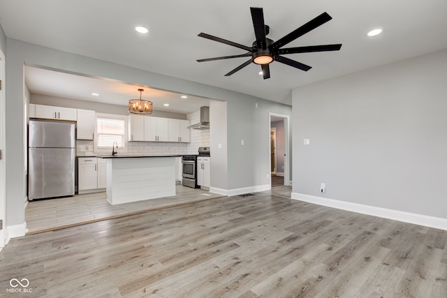 301 Villa Ave, Indianapolis, IN 46201 - kitchen featuring tasteful backsplash, light wood-type flooring, ceiling fan with notable chandelier, stainless steel appliances, and wall chimney exhaust hood
