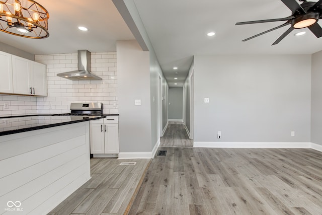 301 Villa Ave, Indianapolis, IN 46201 - kitchen featuring dark countertops, light wood-type flooring, decorative backsplash, ceiling fan with notable chandelier, and wall chimney exhaust hood