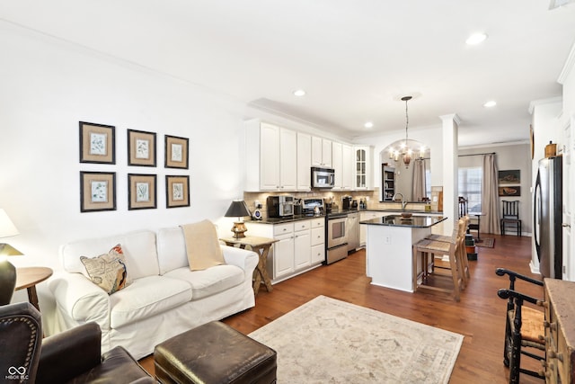 living area featuring recessed lighting, an inviting chandelier, dark wood finished floors, and crown molding