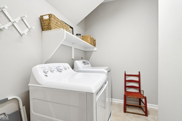 washroom featuring washer and dryer, laundry area, light tile patterned floors, and baseboards