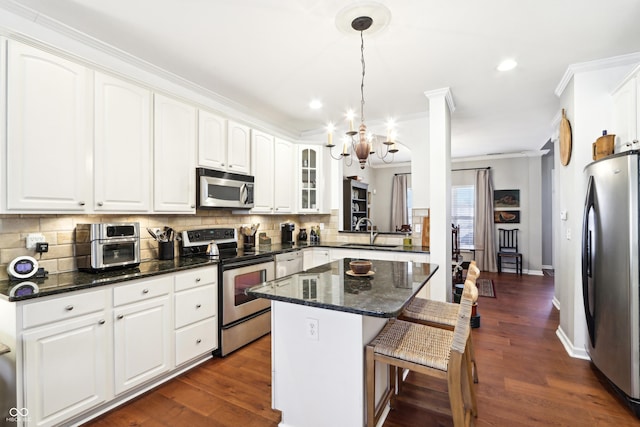 kitchen featuring tasteful backsplash, a kitchen island, a chandelier, a kitchen breakfast bar, and stainless steel appliances