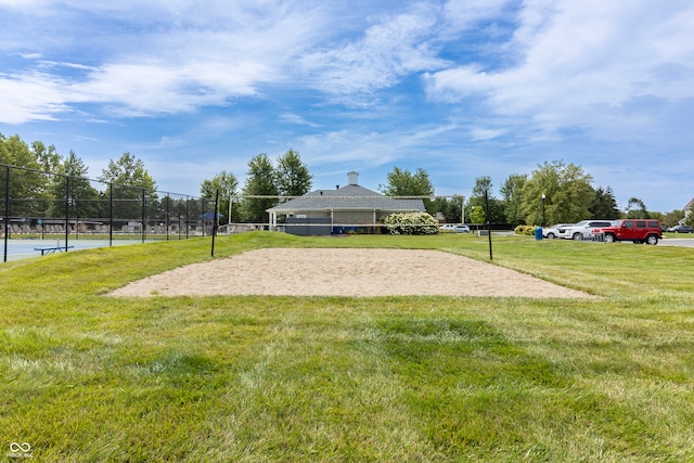 view of home's community with a lawn, volleyball court, and fence