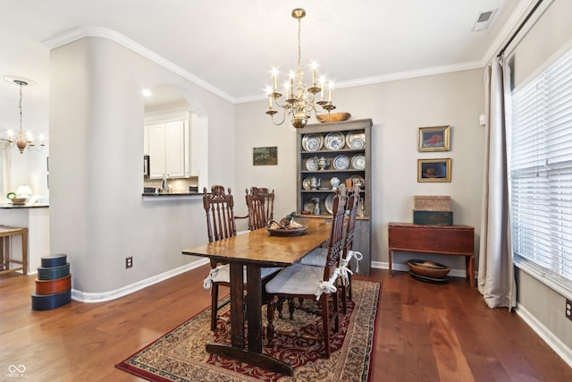 dining area with an inviting chandelier, crown molding, wood finished floors, and arched walkways