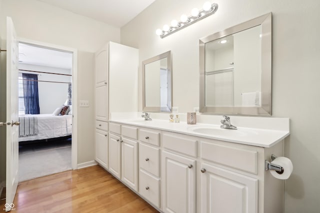 full bathroom with an enclosed shower, a sink, ensuite bath, wood finished floors, and double vanity