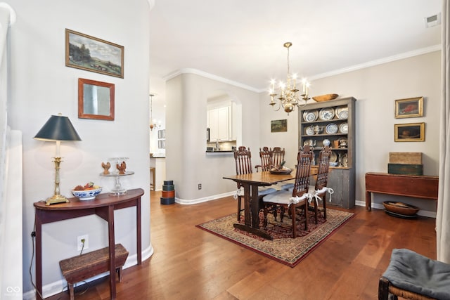 dining room featuring dark wood finished floors, visible vents, an inviting chandelier, and ornamental molding