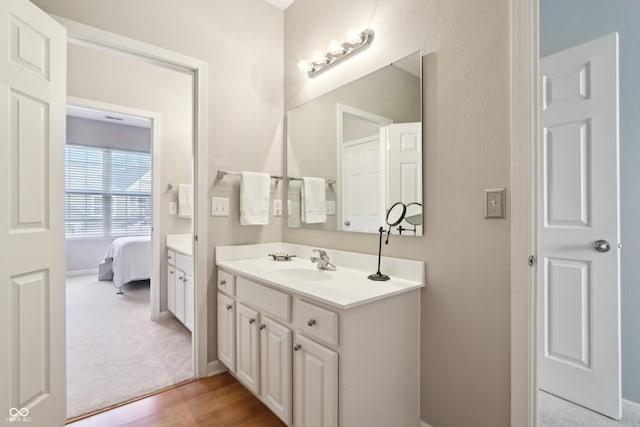 bathroom featuring connected bathroom, vanity, and wood finished floors