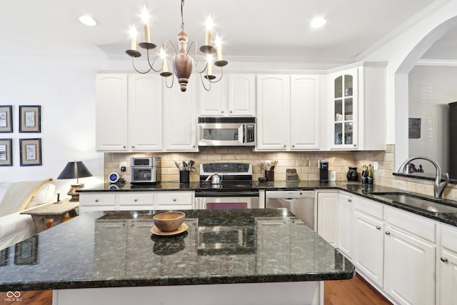 kitchen featuring a notable chandelier, a sink, arched walkways, appliances with stainless steel finishes, and decorative backsplash