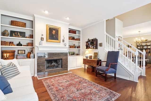 living area with a high end fireplace, ornamental molding, stairs, and wood finished floors