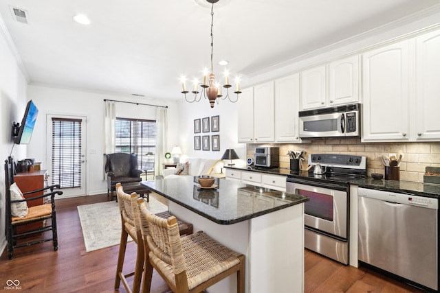 kitchen with stainless steel appliances, tasteful backsplash, a chandelier, and dark wood finished floors