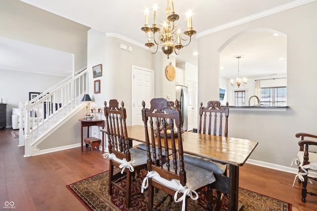 dining area with baseboards, wood finished floors, arched walkways, and a chandelier