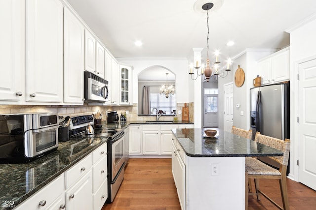 kitchen featuring a breakfast bar, a sink, appliances with stainless steel finishes, decorative backsplash, and a chandelier