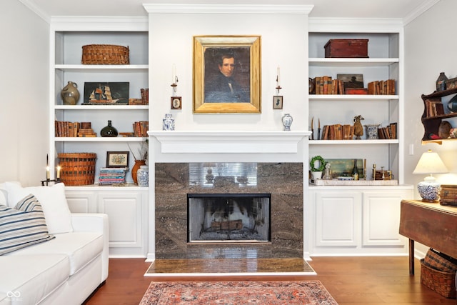 living area with built in features, crown molding, and wood finished floors