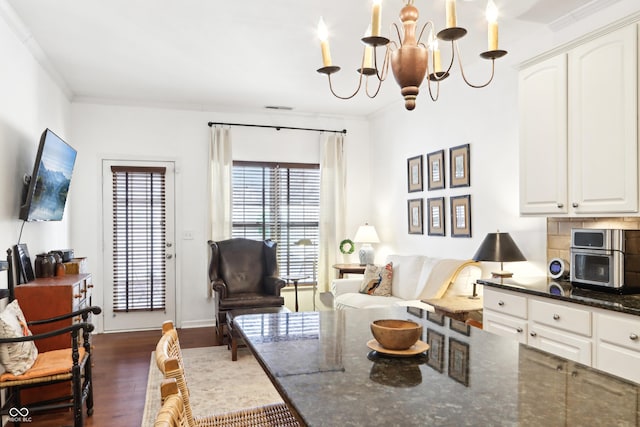 living room featuring visible vents, a notable chandelier, wood finished floors, and crown molding