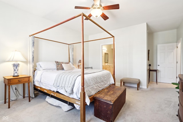 bedroom with ensuite bath, light colored carpet, a ceiling fan, and baseboards