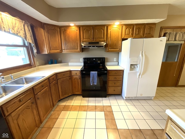 kitchen featuring under cabinet range hood, a sink, white refrigerator with ice dispenser, black range with electric cooktop, and brown cabinetry