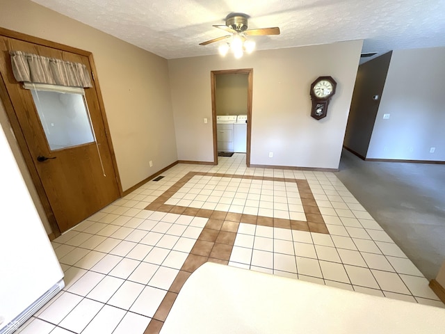 empty room featuring light tile patterned floors, baseboards, a textured ceiling, and washer and clothes dryer