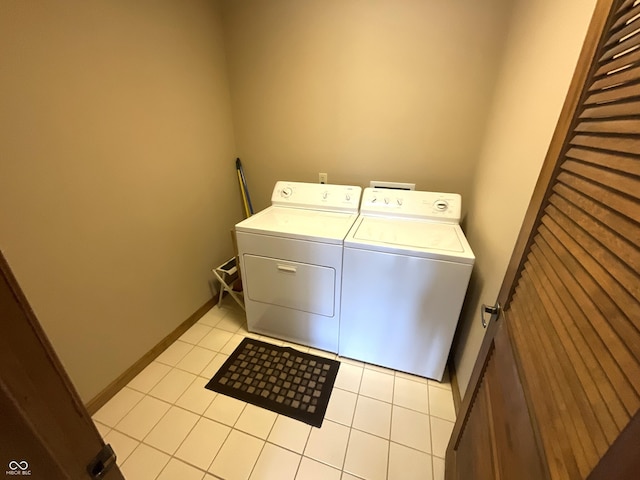 clothes washing area featuring light tile patterned floors, laundry area, washer and dryer, and baseboards