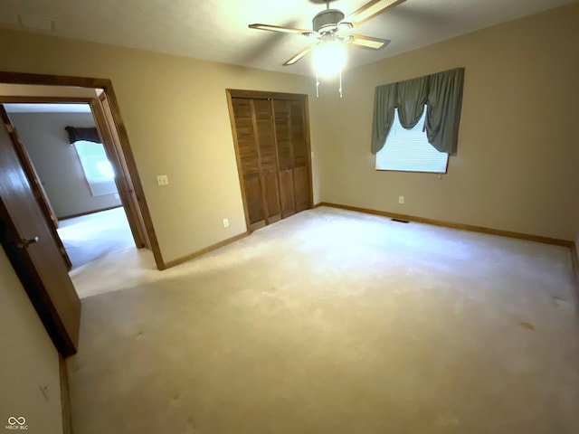 unfurnished bedroom with visible vents, baseboards, light colored carpet, a closet, and a ceiling fan