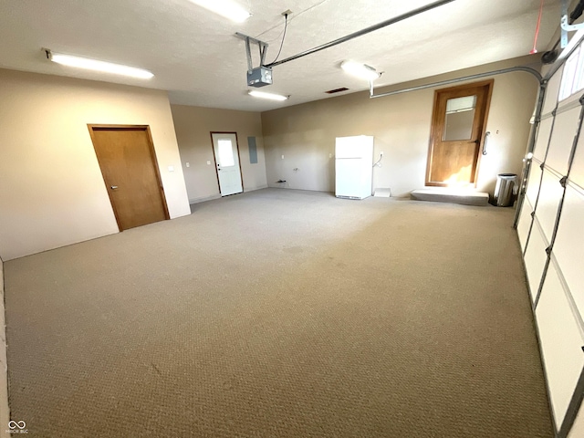 garage with a garage door opener and freestanding refrigerator