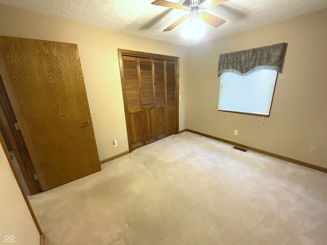 unfurnished bedroom with light carpet, a closet, a textured ceiling, and baseboards