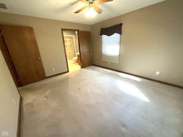 unfurnished bedroom featuring a ceiling fan, visible vents, baseboards, ensuite bathroom, and light colored carpet