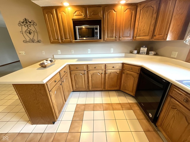 kitchen with brown cabinets, stainless steel microwave, black dishwasher, a peninsula, and light countertops