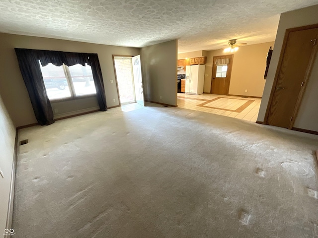 unfurnished living room with visible vents, baseboards, light colored carpet, and a textured ceiling