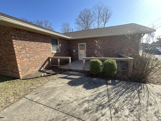 doorway to property with brick siding and a wooden deck