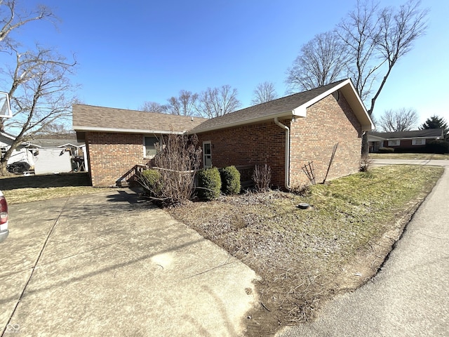 view of home's exterior featuring brick siding and roof with shingles