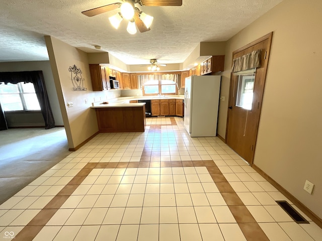 kitchen with visible vents, a healthy amount of sunlight, light tile patterned flooring, and freestanding refrigerator