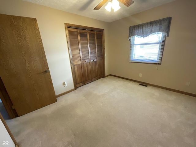 unfurnished bedroom featuring baseboards, light carpet, visible vents, and a closet