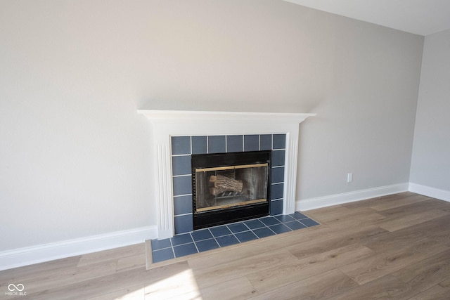 interior details with baseboards, wood finished floors, and a tile fireplace