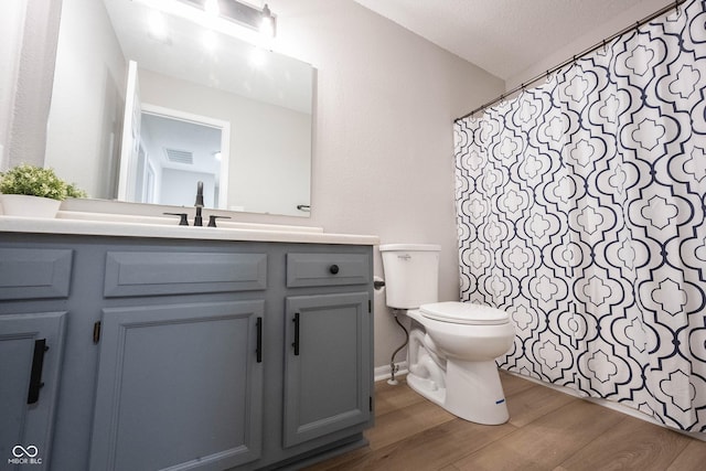 bathroom with visible vents, toilet, a shower with shower curtain, wood finished floors, and vanity