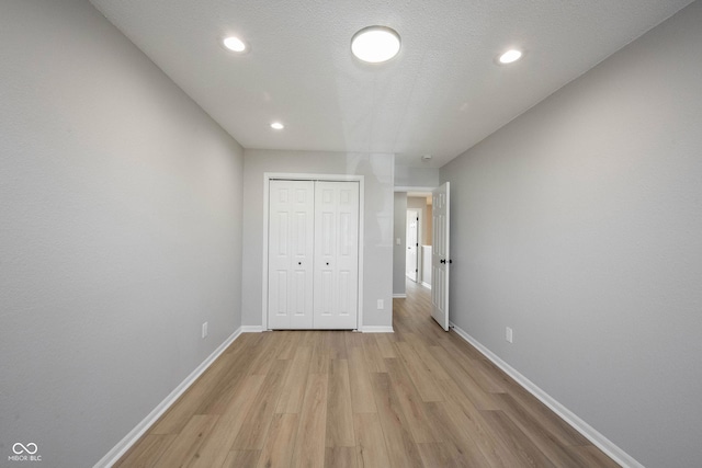 unfurnished bedroom with light wood finished floors, baseboards, recessed lighting, a closet, and a textured ceiling