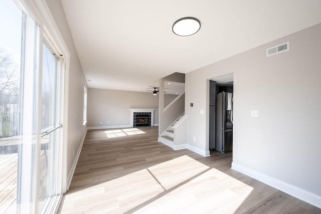 unfurnished living room featuring light wood finished floors, visible vents, a fireplace, and baseboards