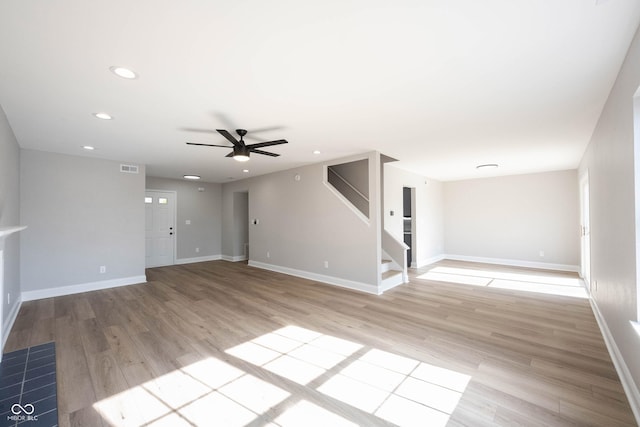 unfurnished living room featuring light wood-type flooring, stairway, baseboards, and recessed lighting