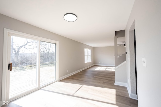 spare room with a ceiling fan, stairway, wood finished floors, and baseboards