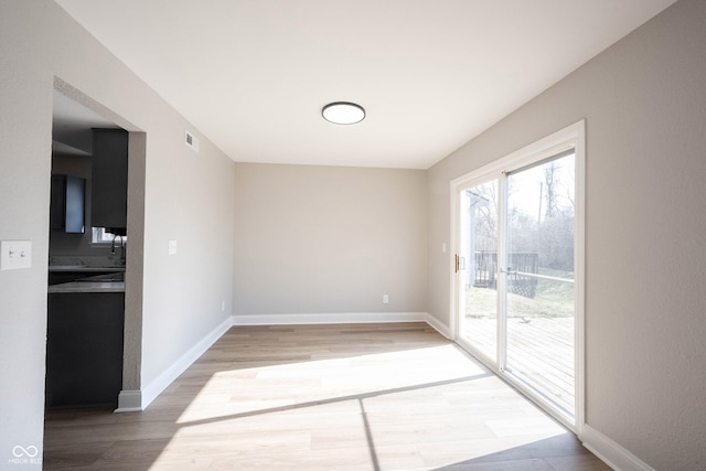 spare room with visible vents, baseboards, and light wood-style floors