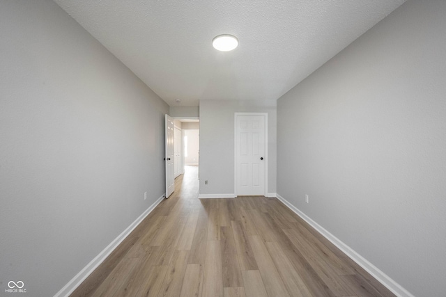 unfurnished bedroom with baseboards, light wood-type flooring, and a textured ceiling