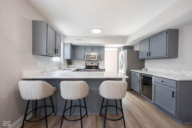 kitchen with visible vents, a sink, wine cooler, appliances with stainless steel finishes, and a peninsula