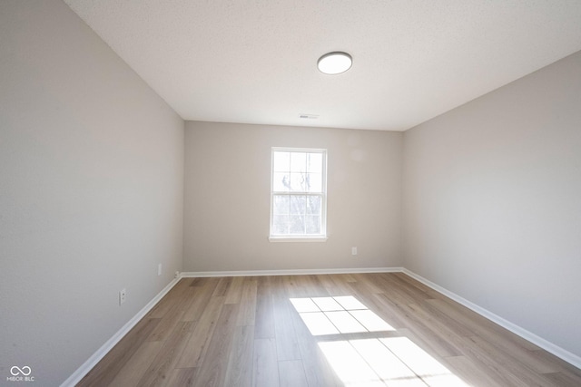 spare room featuring visible vents, light wood-type flooring, and baseboards