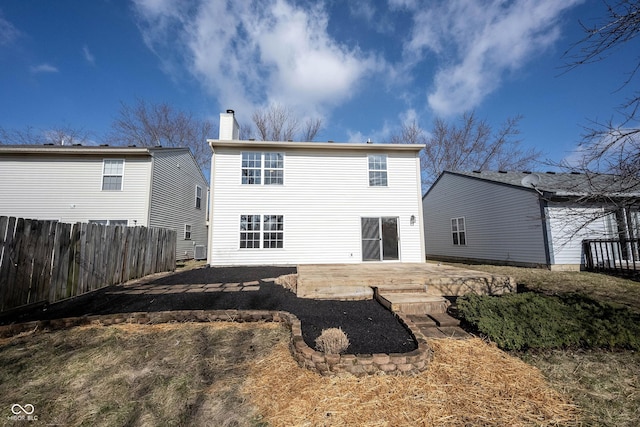 rear view of property featuring a chimney, a patio, and fence