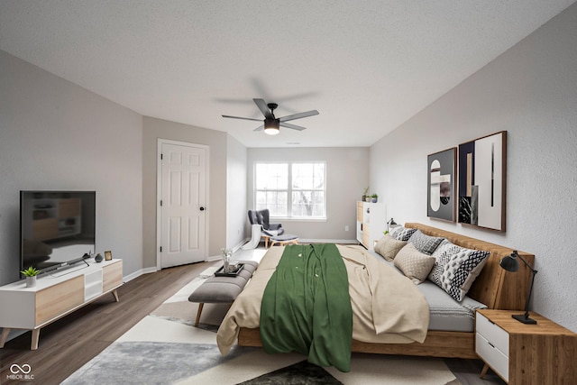 bedroom with a textured ceiling, baseboards, a ceiling fan, and wood finished floors