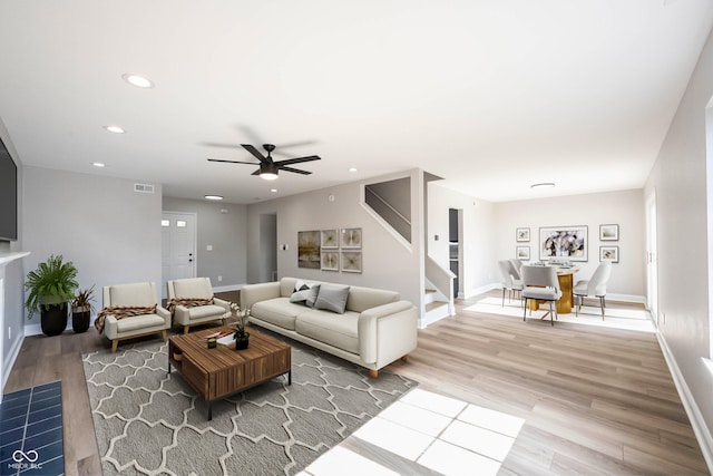 living room with visible vents, recessed lighting, light wood finished floors, baseboards, and stairs