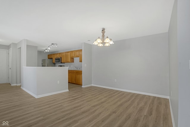 kitchen with baseboards, light wood-style floors, and appliances with stainless steel finishes