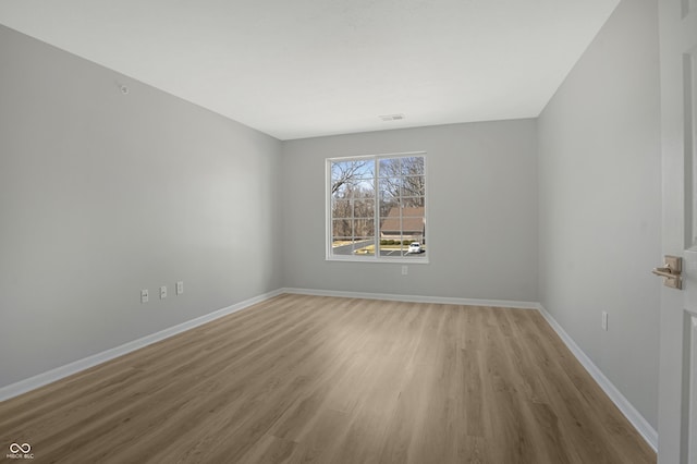 unfurnished room with visible vents, wood finished floors, and baseboards