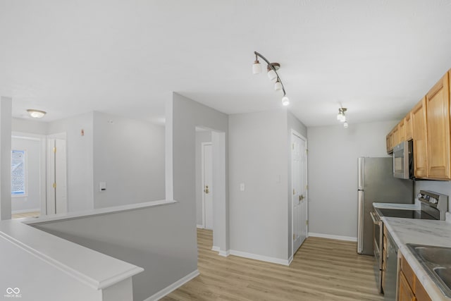 kitchen with stainless steel appliances, baseboards, light countertops, and light wood finished floors