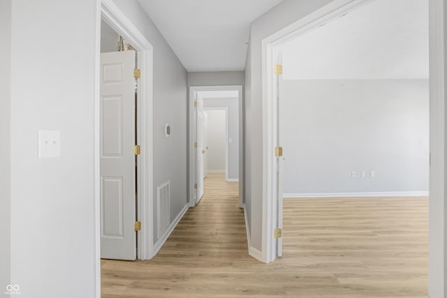 corridor with visible vents, baseboards, and light wood-style floors