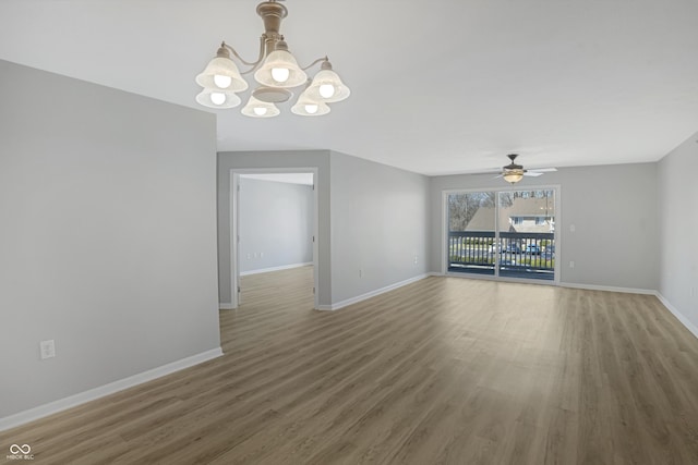 interior space featuring ceiling fan with notable chandelier, wood finished floors, and baseboards