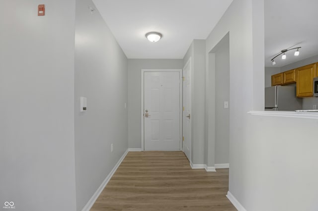 corridor with baseboards and light wood finished floors